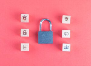 Security concept with lock, icons on wooden cubes on pink background flat lay.